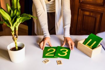 hands of a montessori teacher guide presenting how to make sums