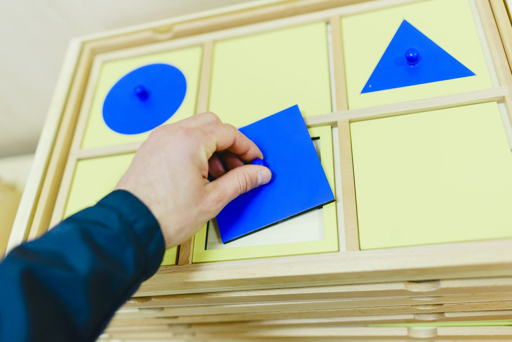 niño manipulando objeto del gabinete de geometría montessori para la coordinación de mano y dedos
