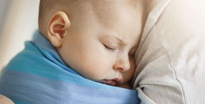 Niño durmiendo sobre el hombre de su madre